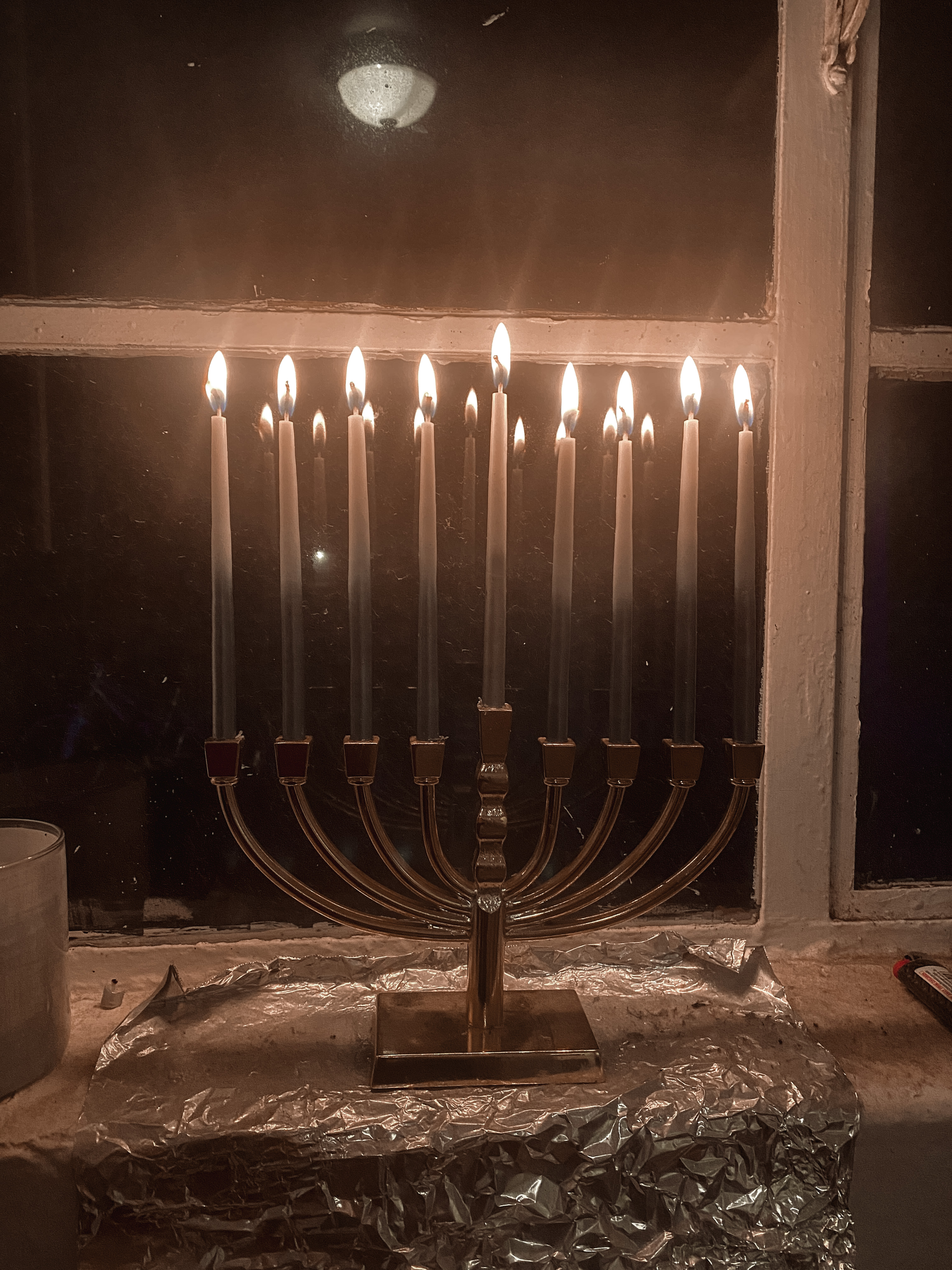 picture of a hanukkah menora with 9 candles in front of a window